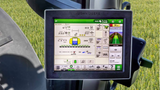 John Deere agricultural machine display screen with control interface on a field background